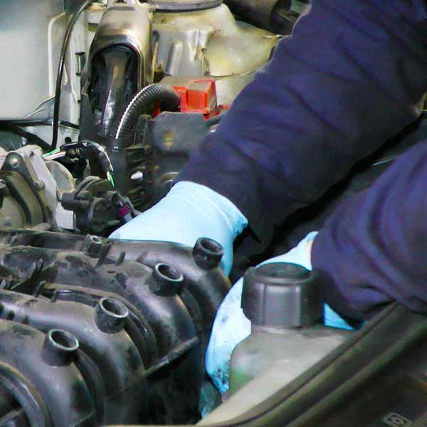 close up view from above of a mechanic servicng a volkswagen car wearing protective blue gloves